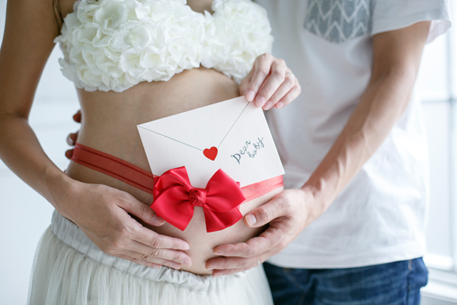パパとママから赤ちゃんへのラブレターを書いてもらい、そのラブレターを使った、おしゃれなマタニティフォト。真っ赤なリボンとラブレターがおしゃれなマタニティ撮影（写真）。2人目妊娠中。