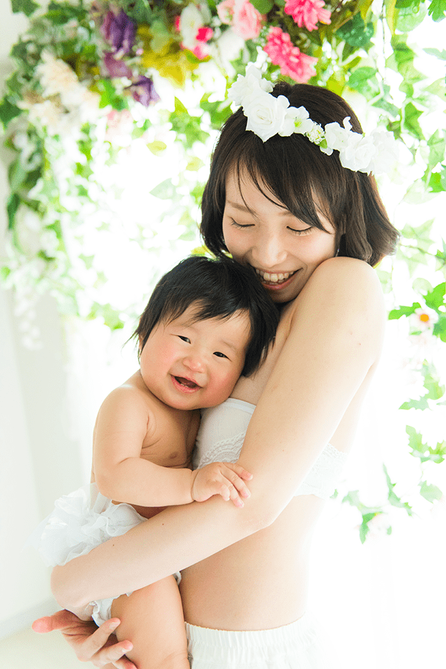 授乳フォト、ベビーフォト、親子フォト。授乳ペイントのコースのデザイン。お母さんが赤ちゃんだきあげている可愛い親子写真。綺麗な自然光と緑がおしゃれな写真。