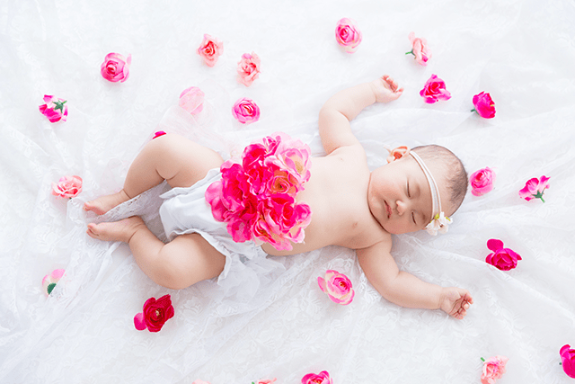 授乳フォト、ベビーフォト、親子フォト。授乳ペイントのコースのデザイン。赤ちゃんが寝ている周りには、ピンクと赤のお花が散りばめられている、おしゃれなベビーフォト。プロ女性カメラマンによる撮影。